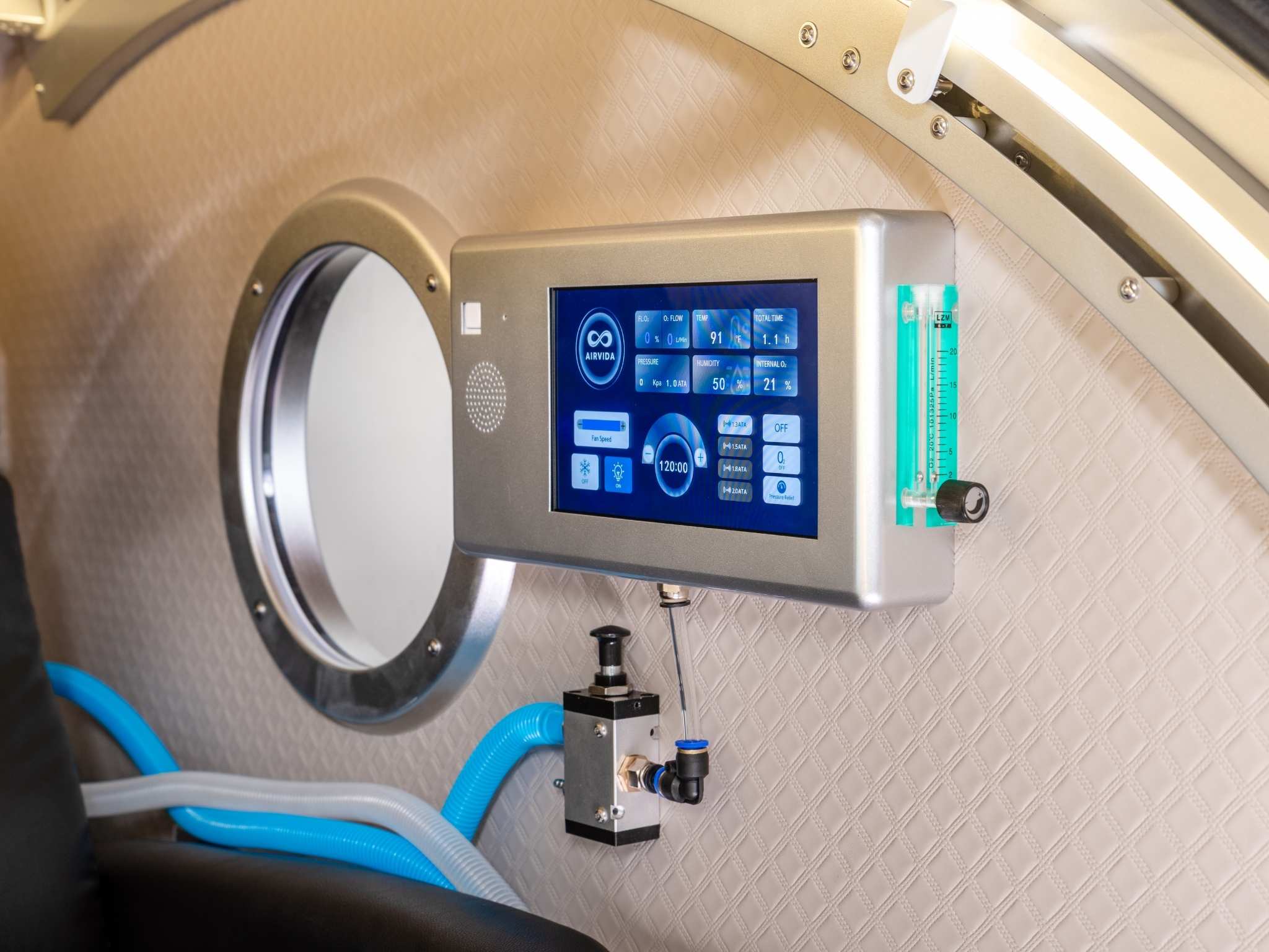 Close-up of a hyperbaric oxygen chamber control panel with touchscreen interface, oxygen flow meter, and observation window.