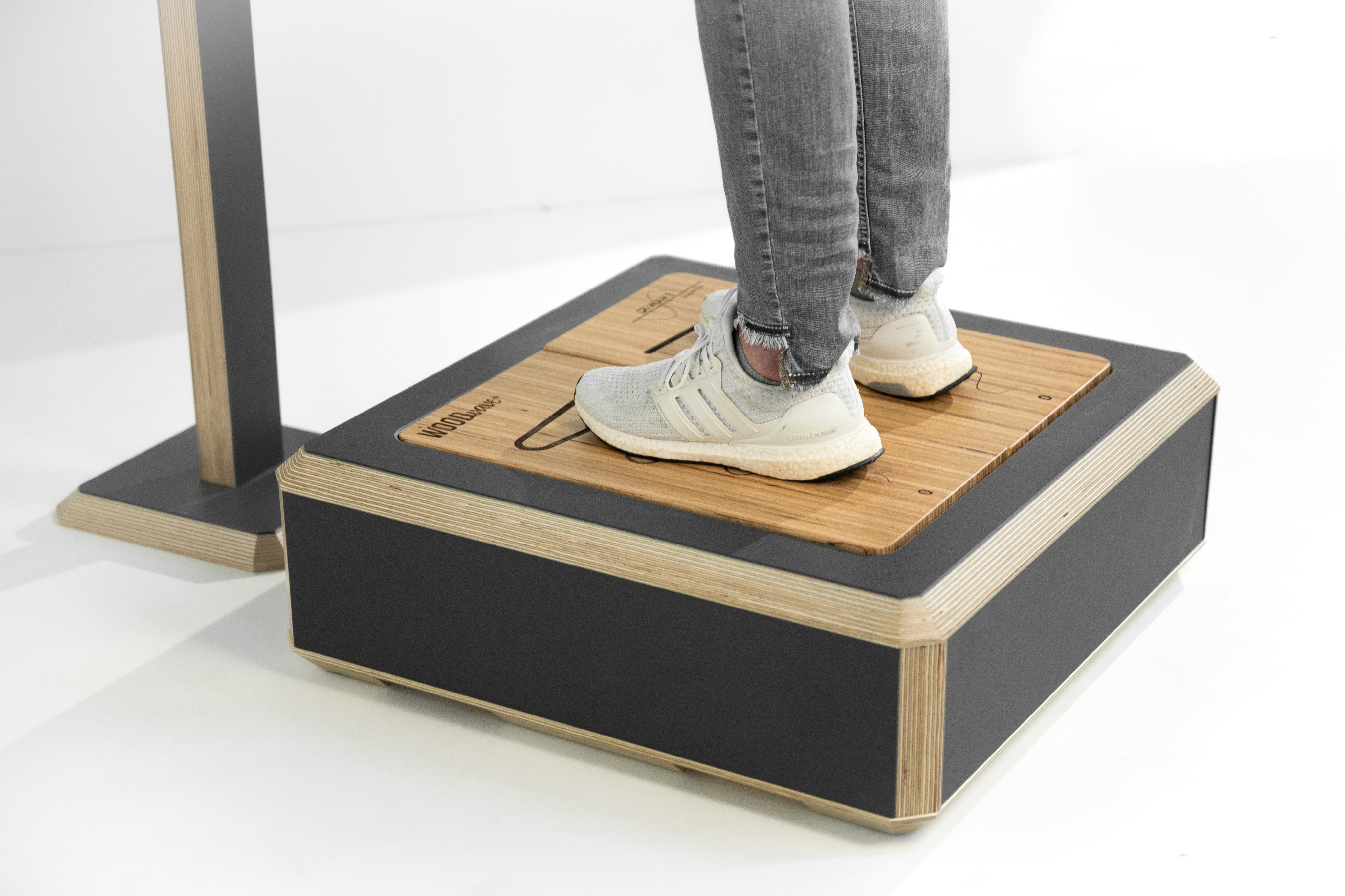 Person stepping onto a wooden platform with a black base on a white background