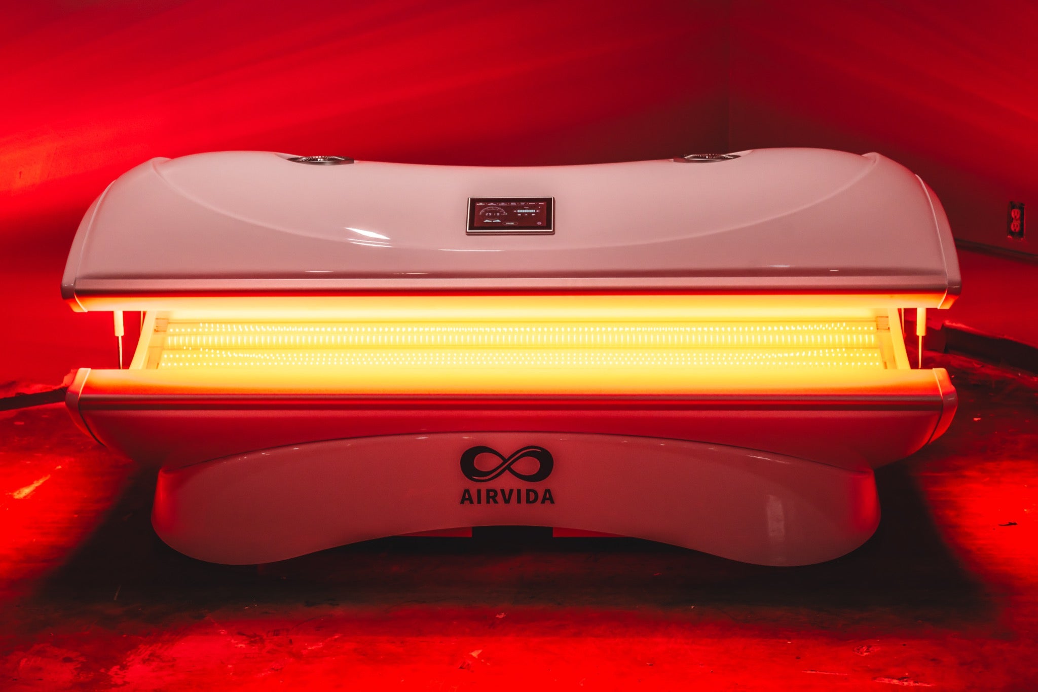AIRVIDA red light therapy bed glowing with bright LED panels, featuring a sleek white canopy, touchscreen control, and full-body treatment design.
