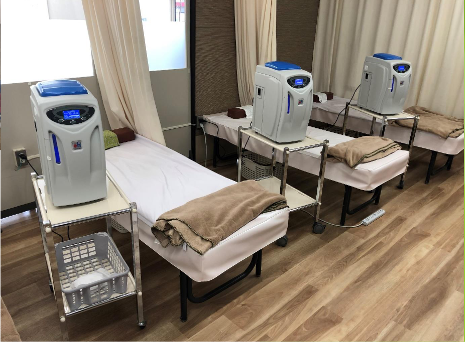 Three Airvida Hydrogen Inhalation Machines H2JI1 sit on carts next to treatment beds in a clinic