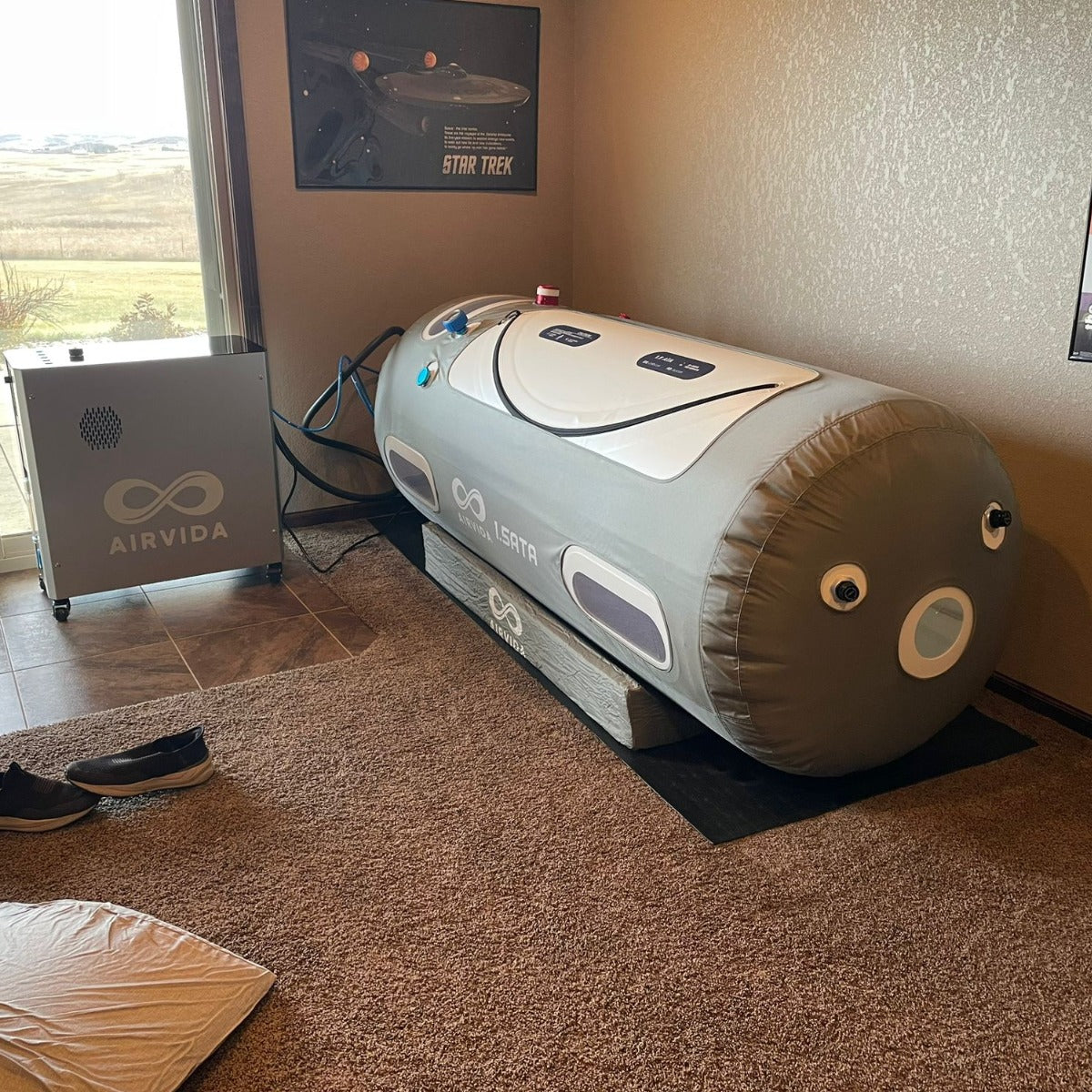 An Airvida 1.5ATA hyperbaric chamber by a window