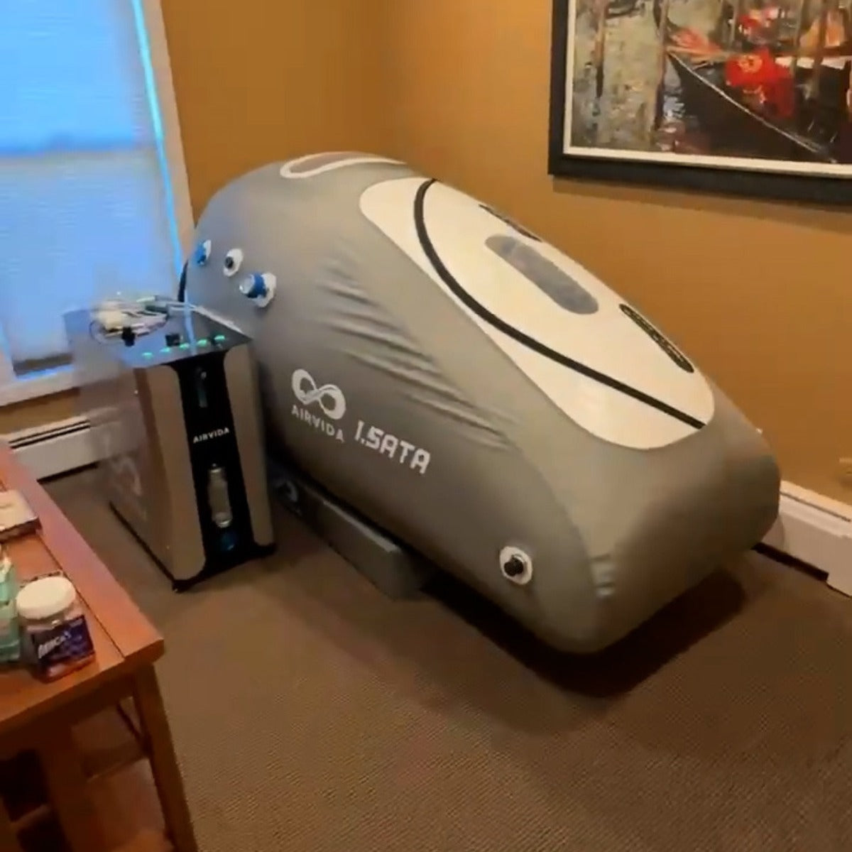 An Airvida 1.5ATA hyperbaric chamber and its compressor unit sit on a carpeted floor.