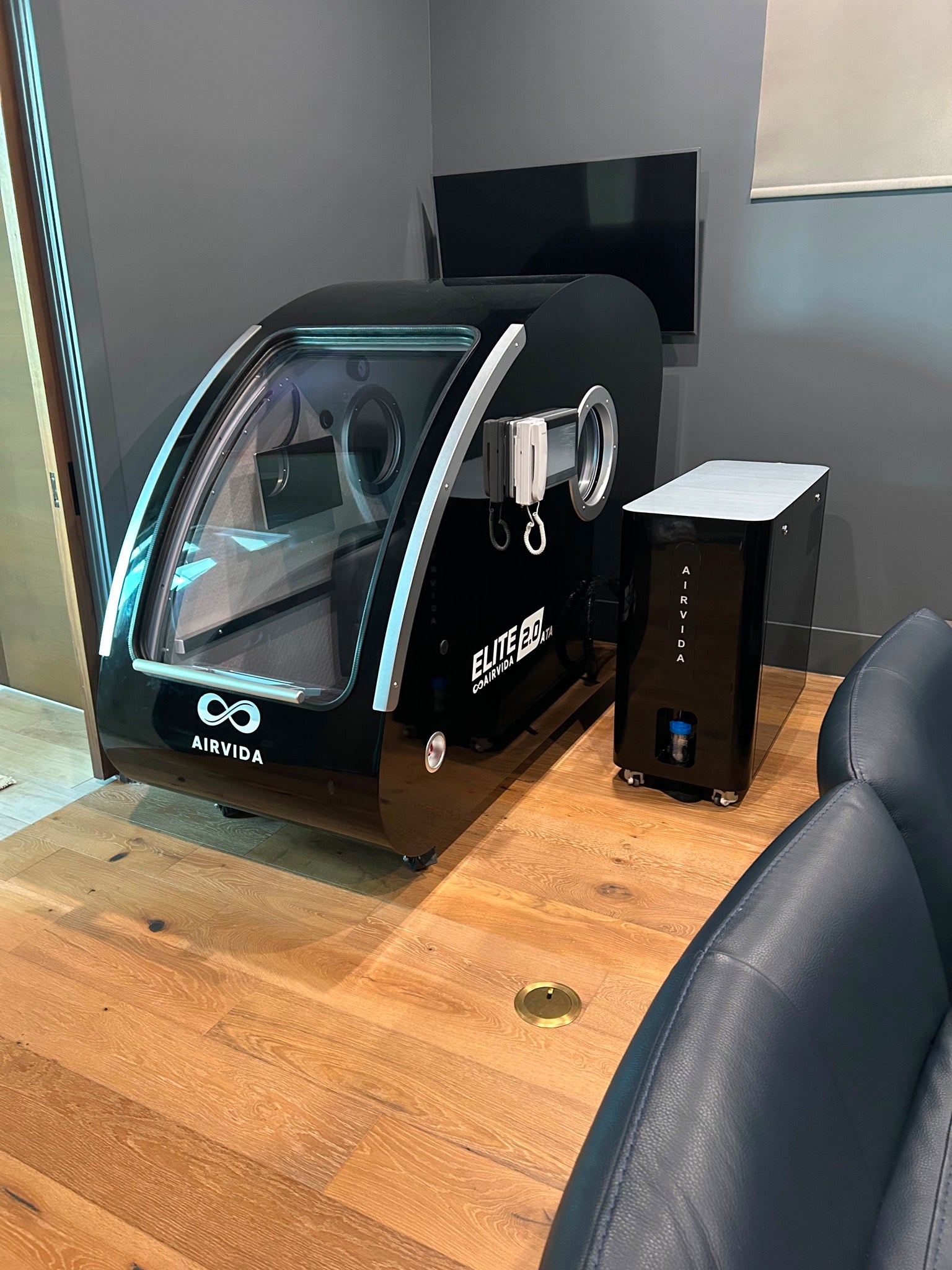 Airvida Elite 2.0 ATA hard-shell hyperbaric chamber with oxygen system installed in a modern home wellness room.