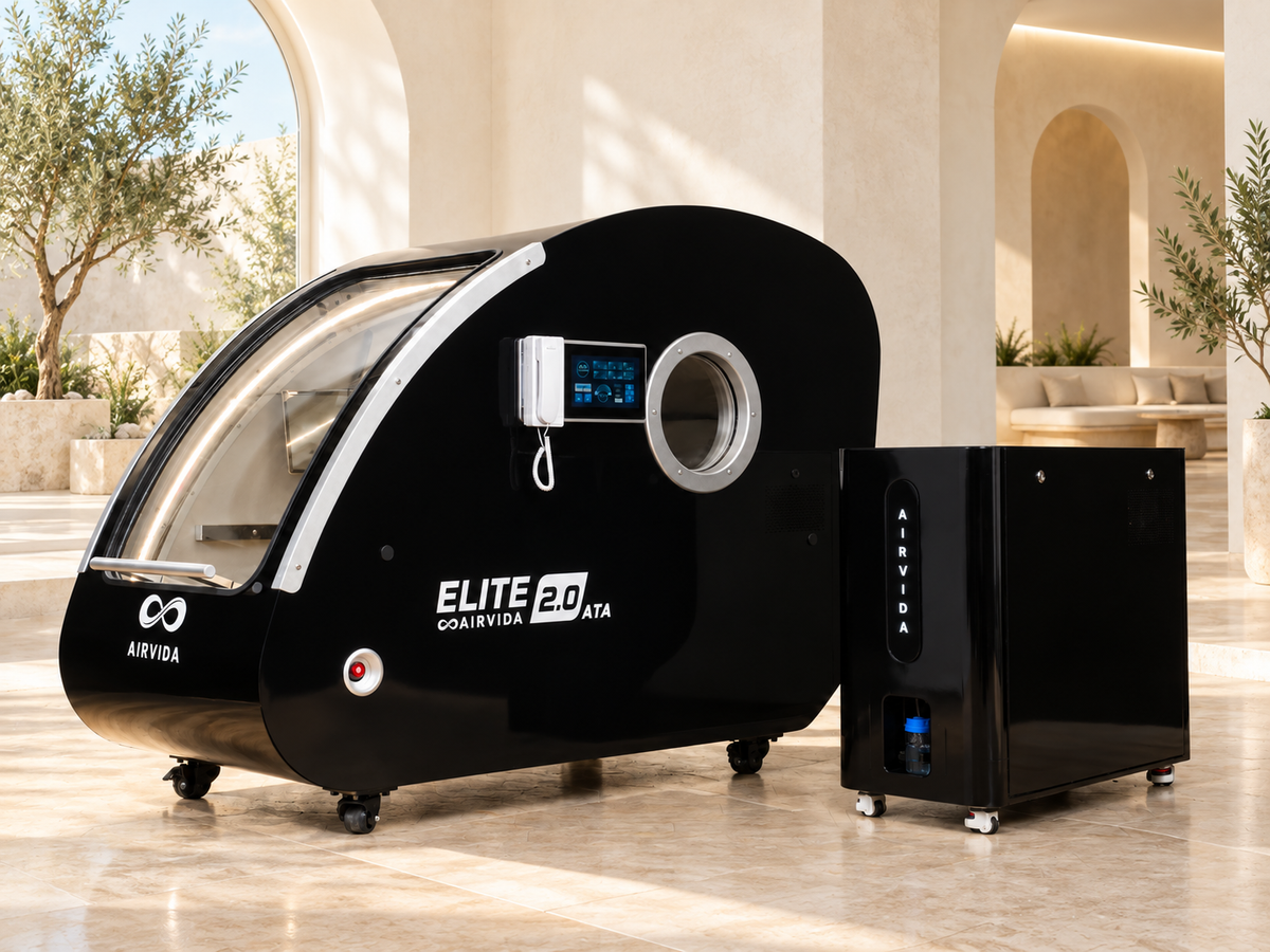 Black Airvida Elite 2.0 hyperbaric chamber and oxygen system displayed in a bright, luxury wellness space with arched walls, natural light, and indoor greenery.