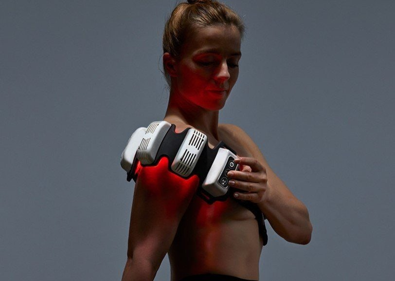 Woman wearing a FlexBeam Portable Red Light Therapy Device against a gray background