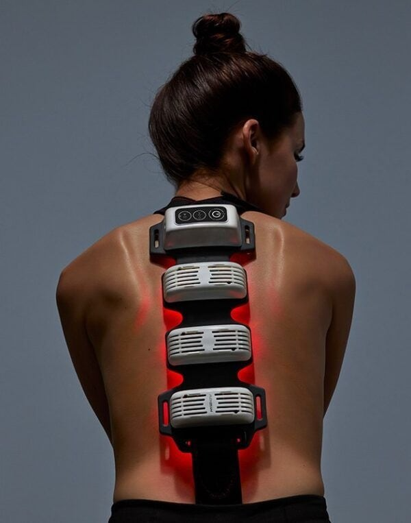 Woman wearing a FlexBeam Portable Red Light Therapy Device on a gray background