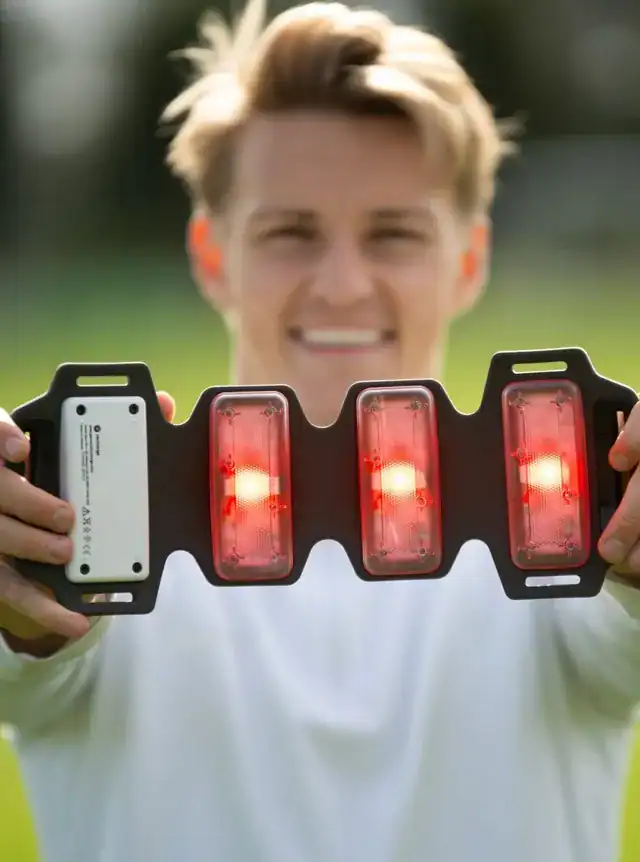 Person holding a FlexBeam Portable Red Light Therapy Device on a blurred green background