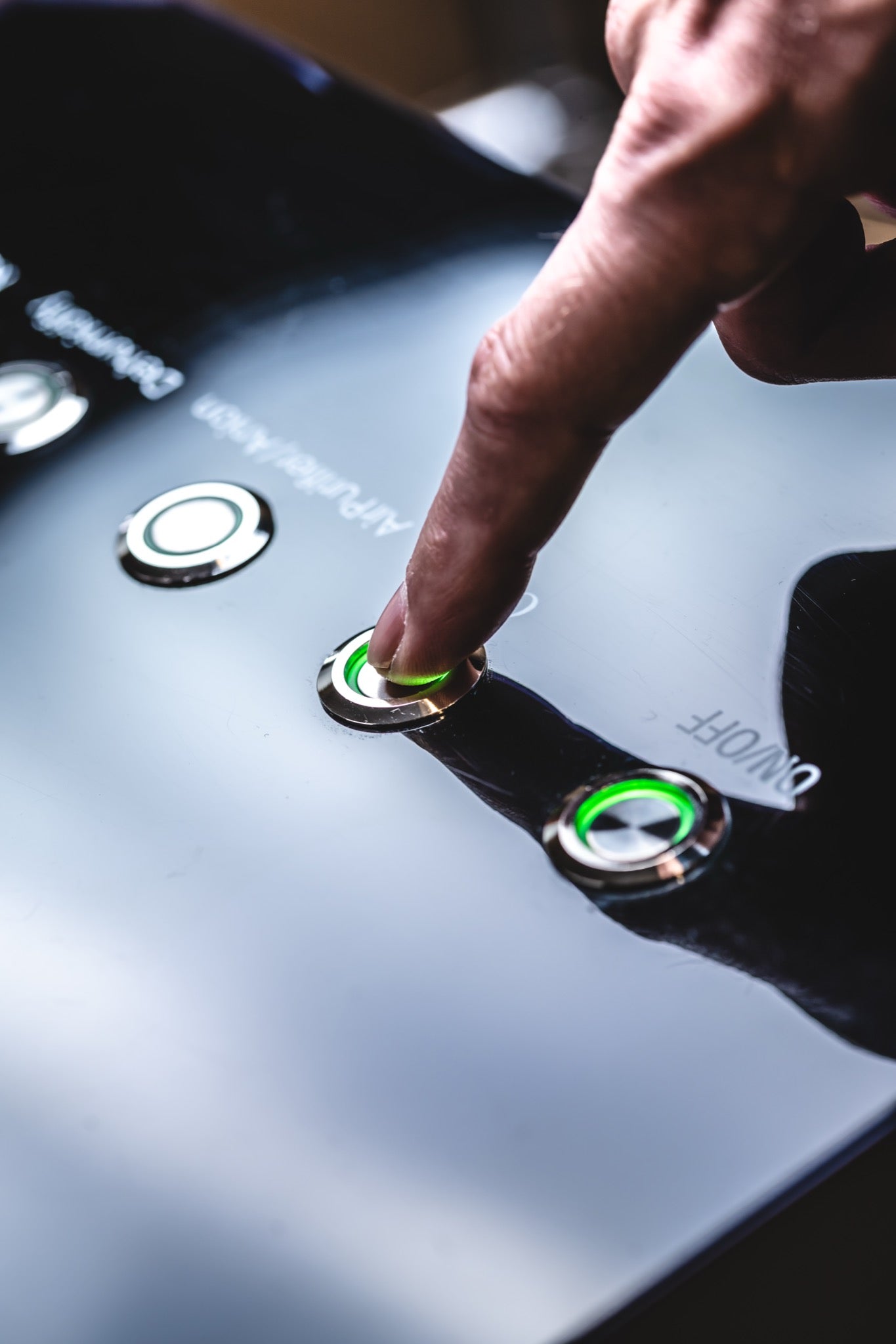 Close-up of a person pressing an illuminated green control button on an AIRVIDA system, highlighting the simple and accessible control interface.
