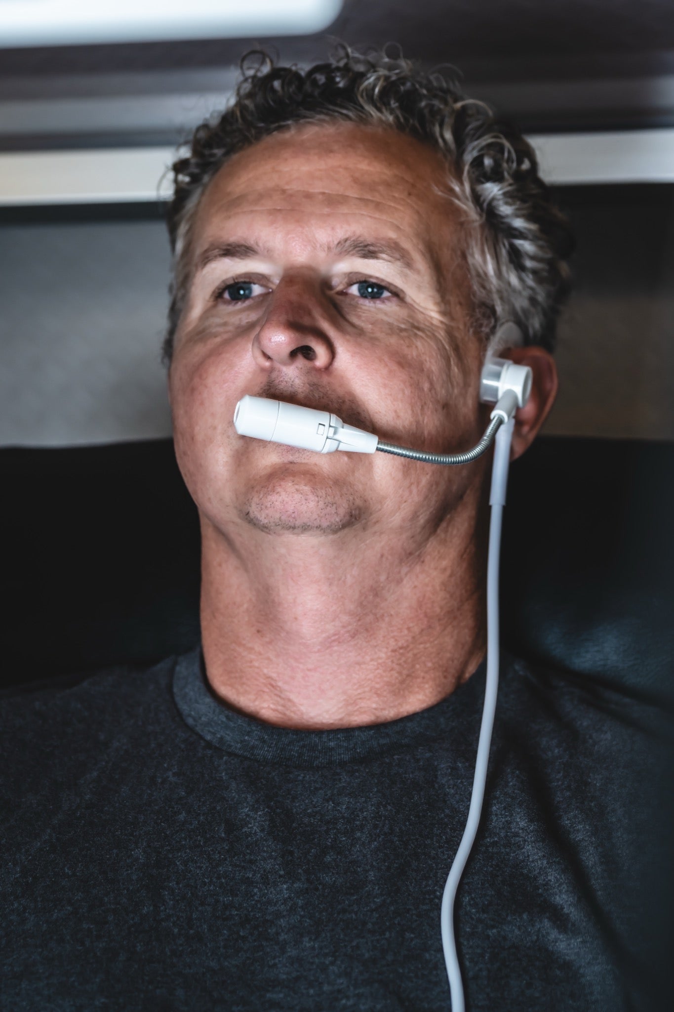 Man using an oxygen breathing device while seated inside a hyperbaric chamber during an HBOT session.