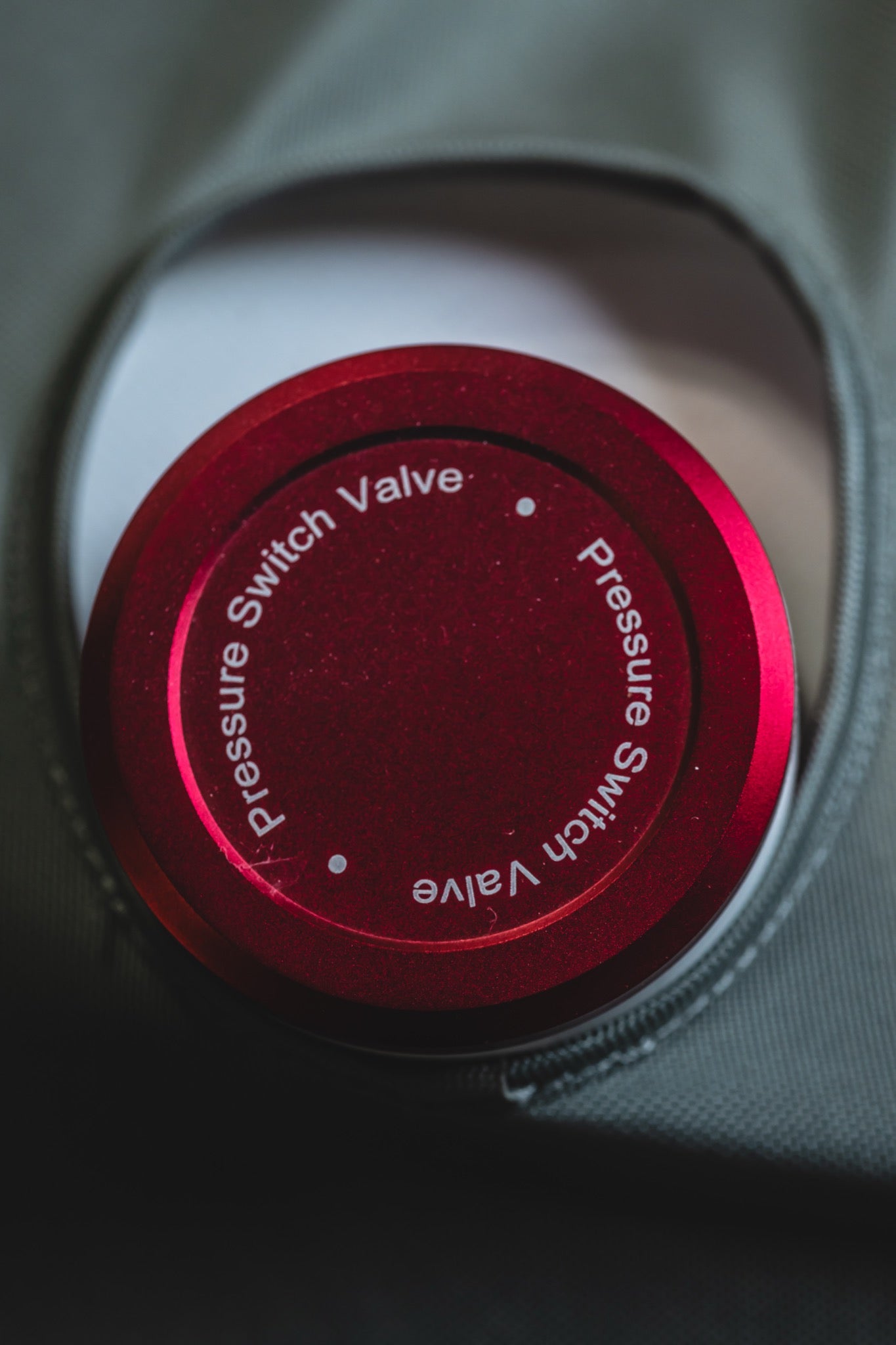 Close-up of a red pressure switch valve on an AIRVIDA soft-shell hyperbaric chamber, positioned within a protective zippered opening for access.