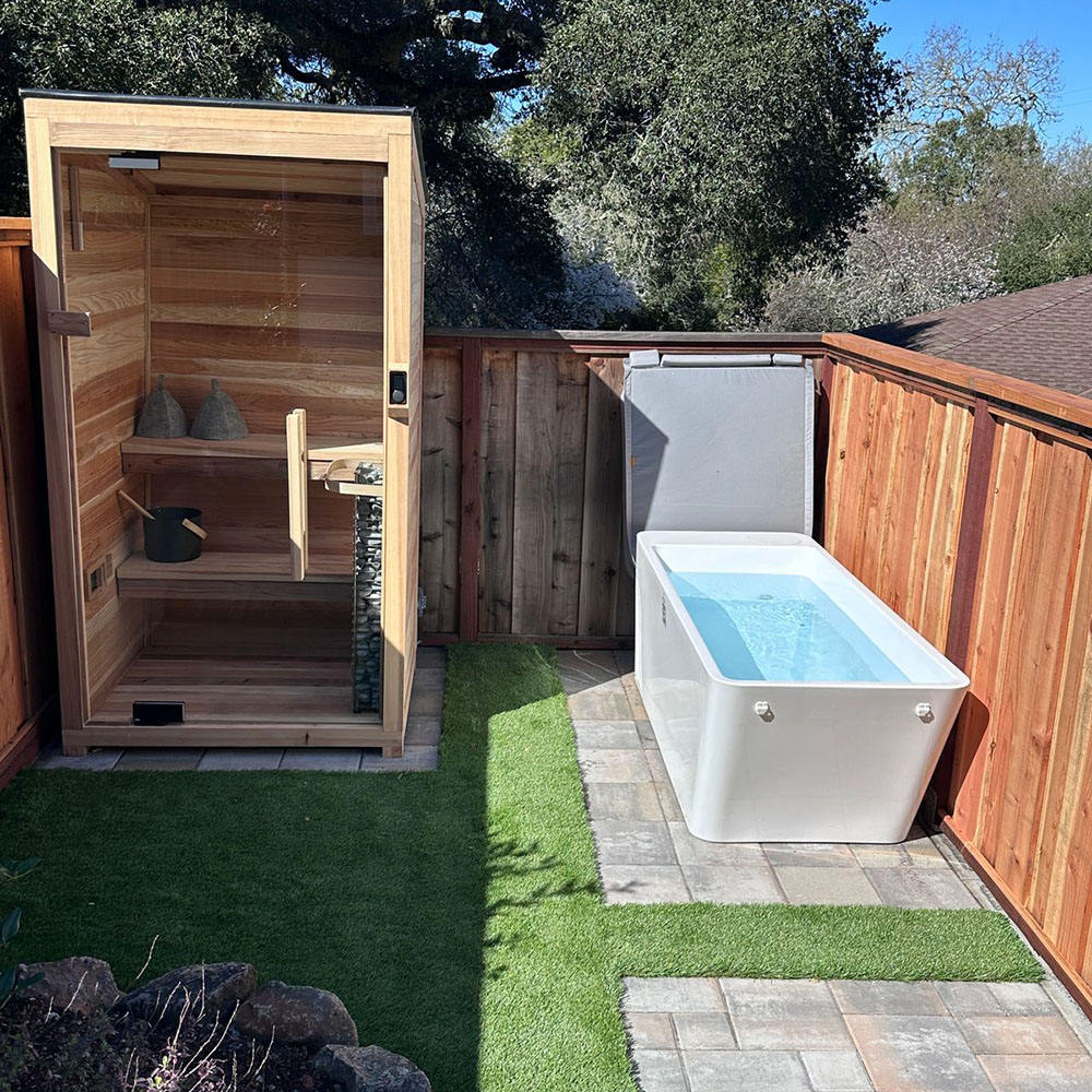Outdoor shower and Airvida Cold Plunge area with wooden enclosure and grassy area.
