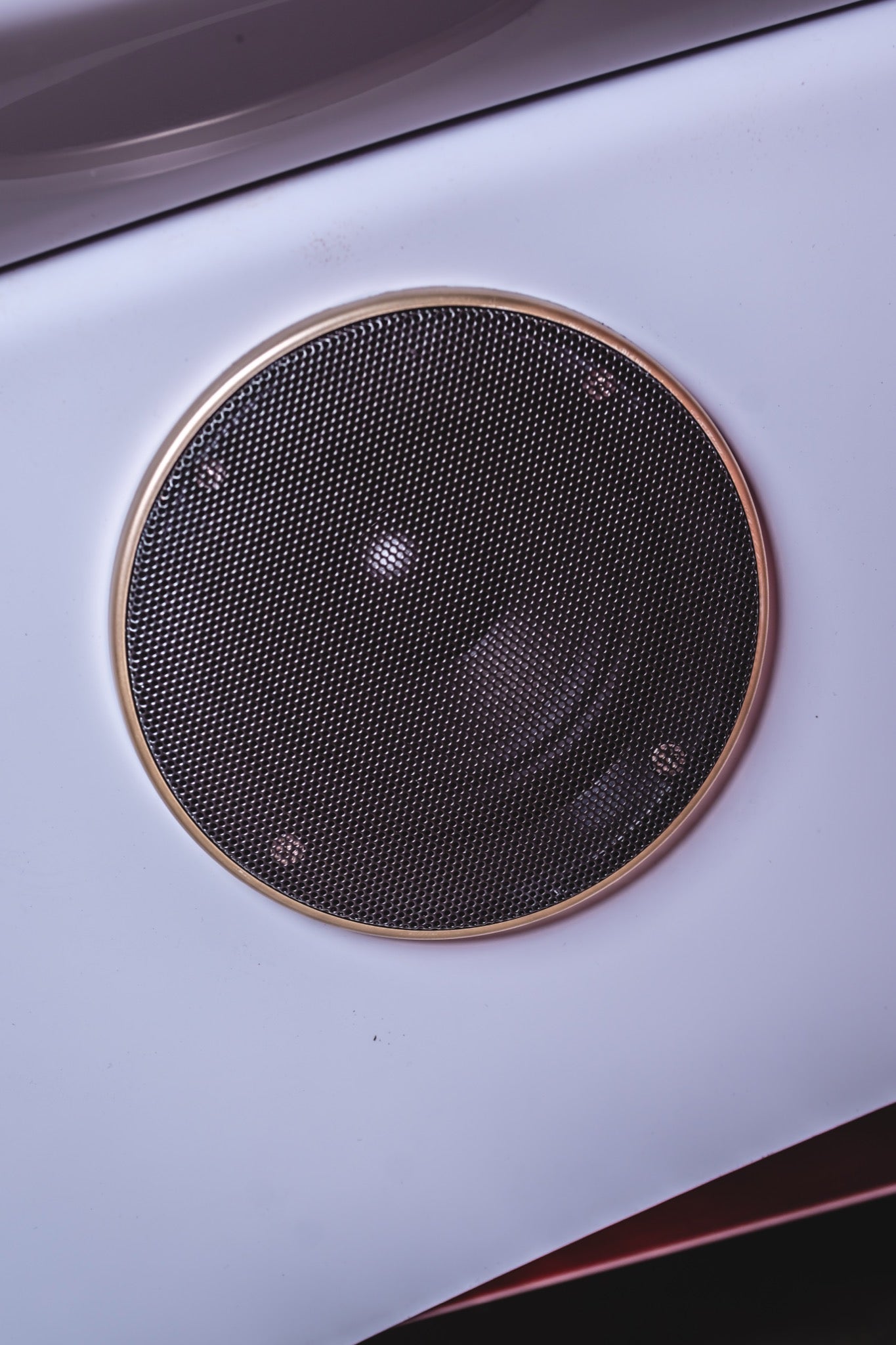 Close-up of a circular ventilation fan with a black mesh grille and metallic trim, integrated into the smooth white exterior of an AIRVIDA unit.