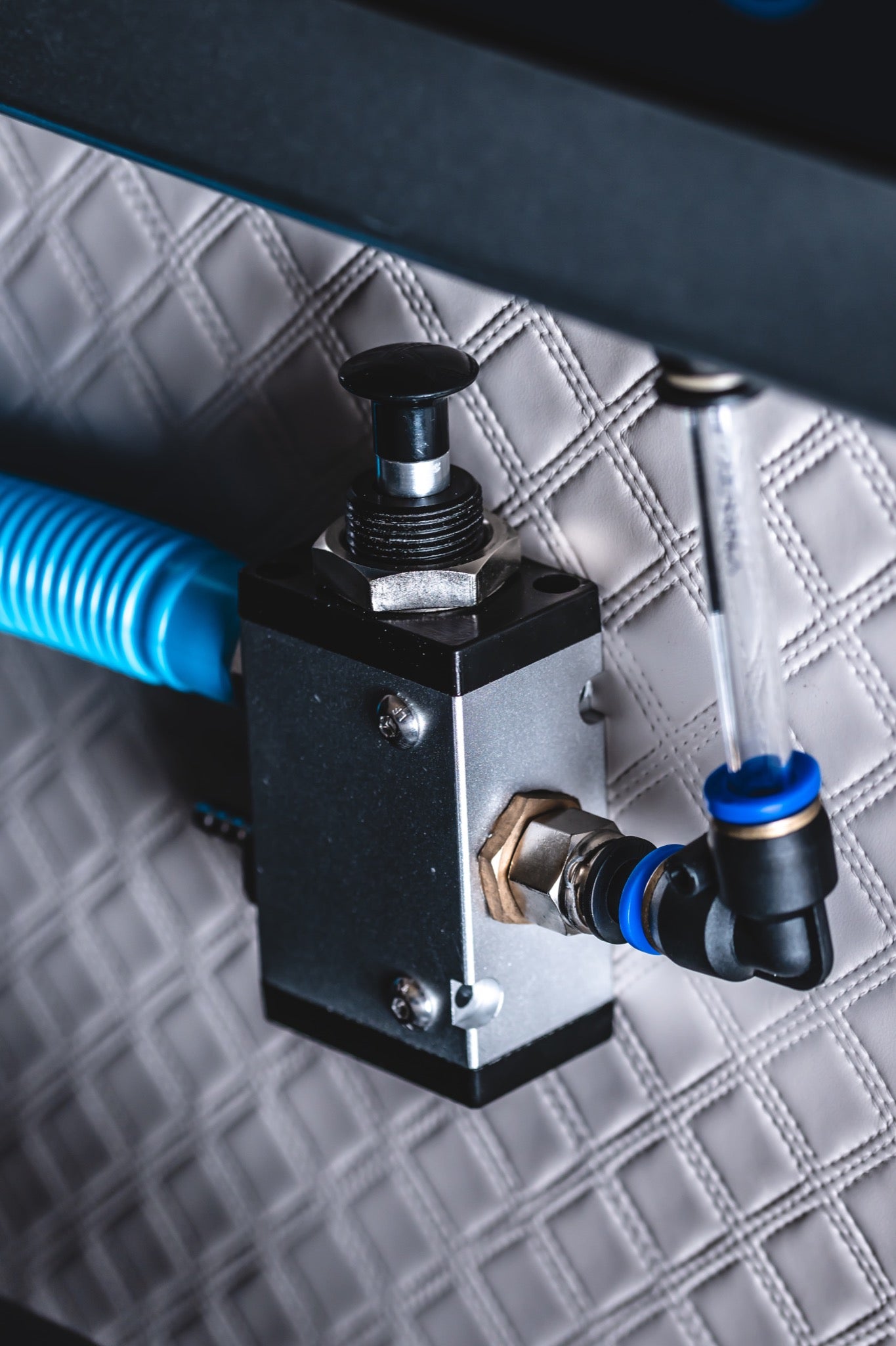 Close-up of an air control valve and tubing inside a quilted hard-shell hyperbaric chamber.