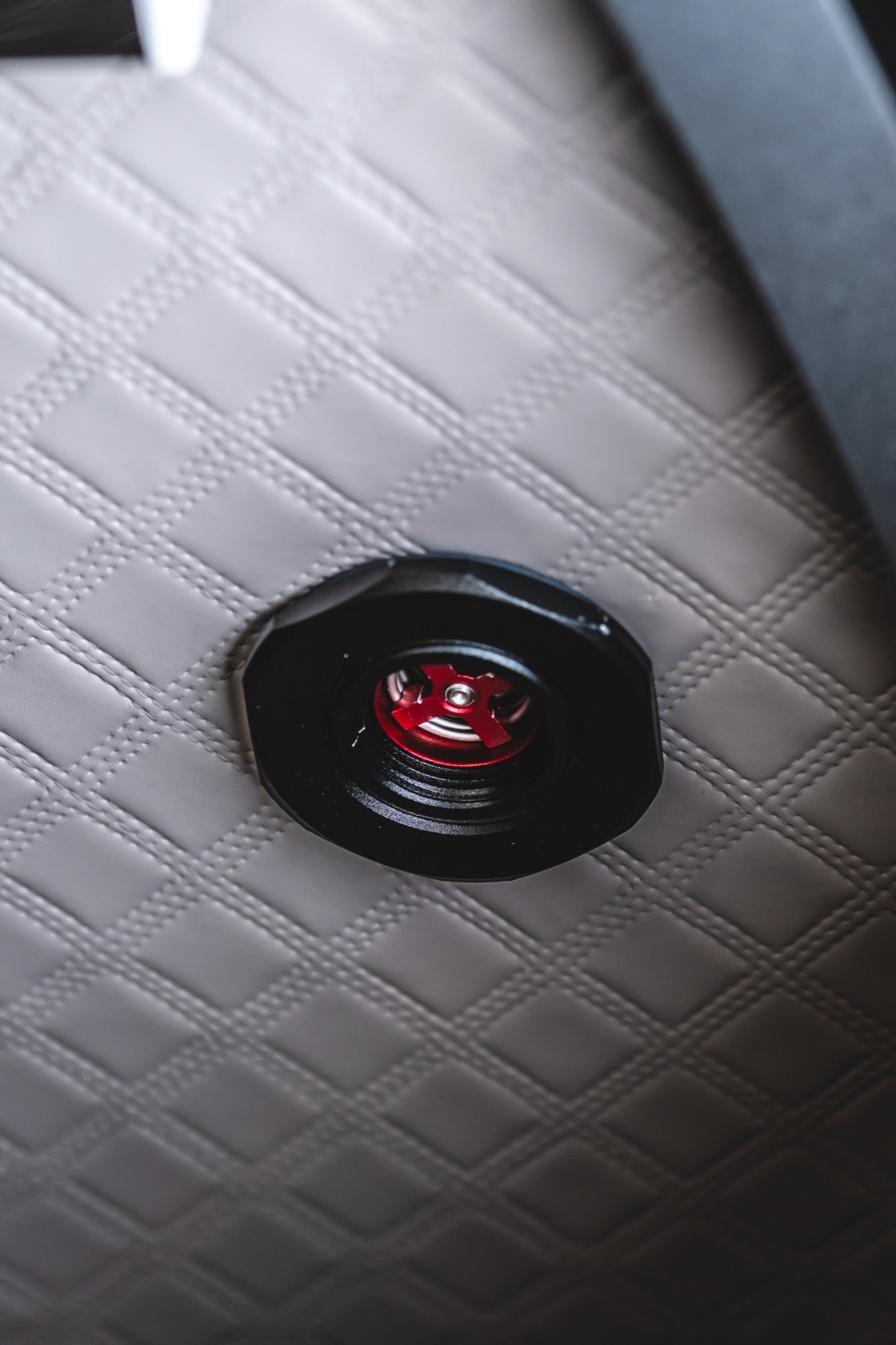 Close-up of a red pressure release valve mounted on the quilted interior wall of a hard-shell hyperbaric chamber.