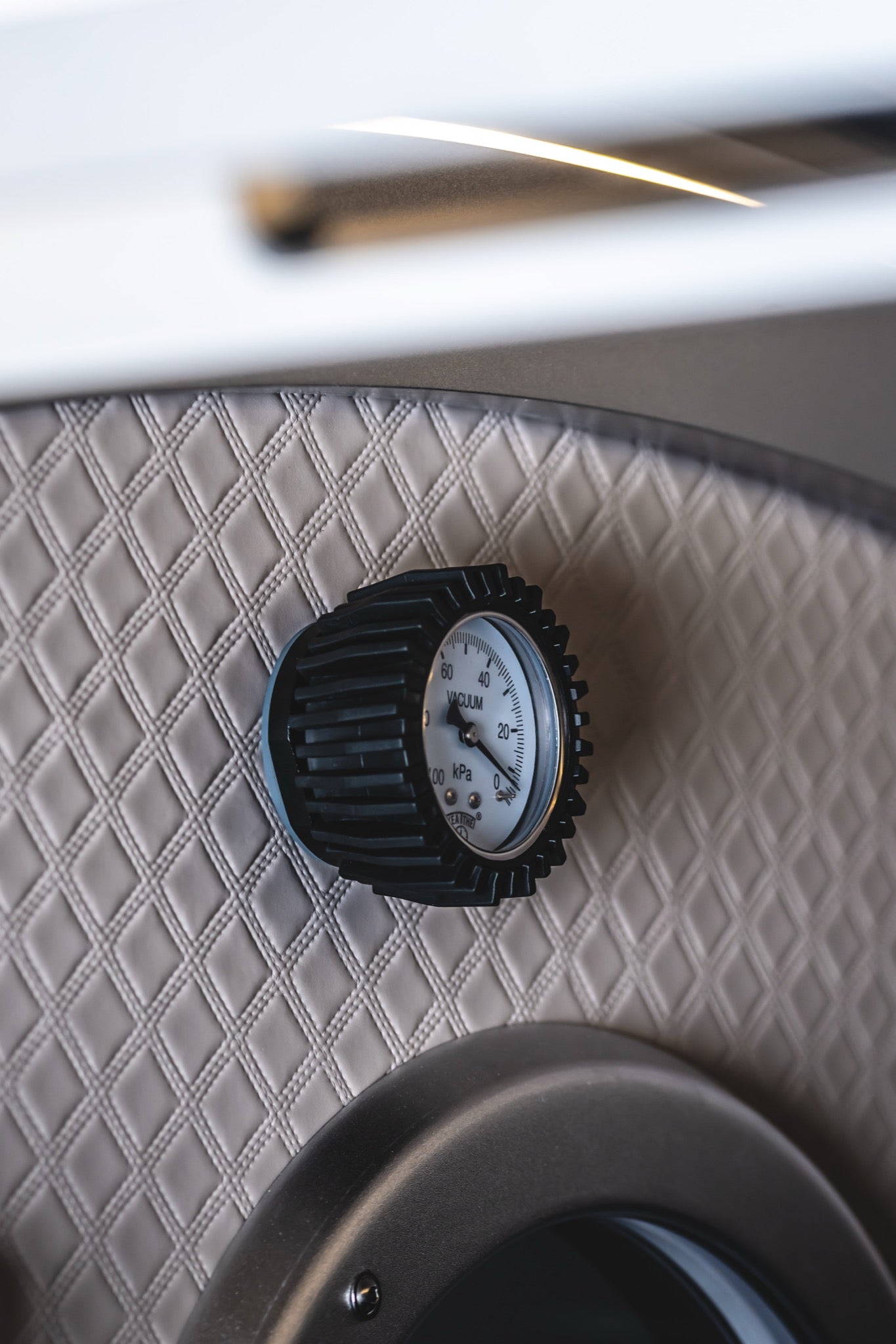 Close-up of a vacuum pressure gauge mounted inside a quilted hard-shell hyperbaric chamber.