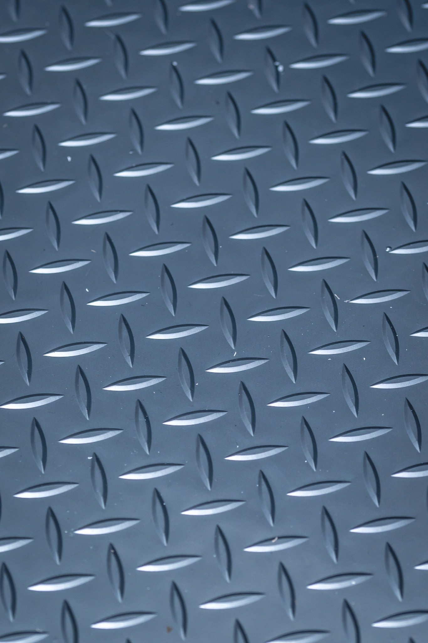 Close-up of a durable blue diamond plate metal surface with a raised textured pattern.