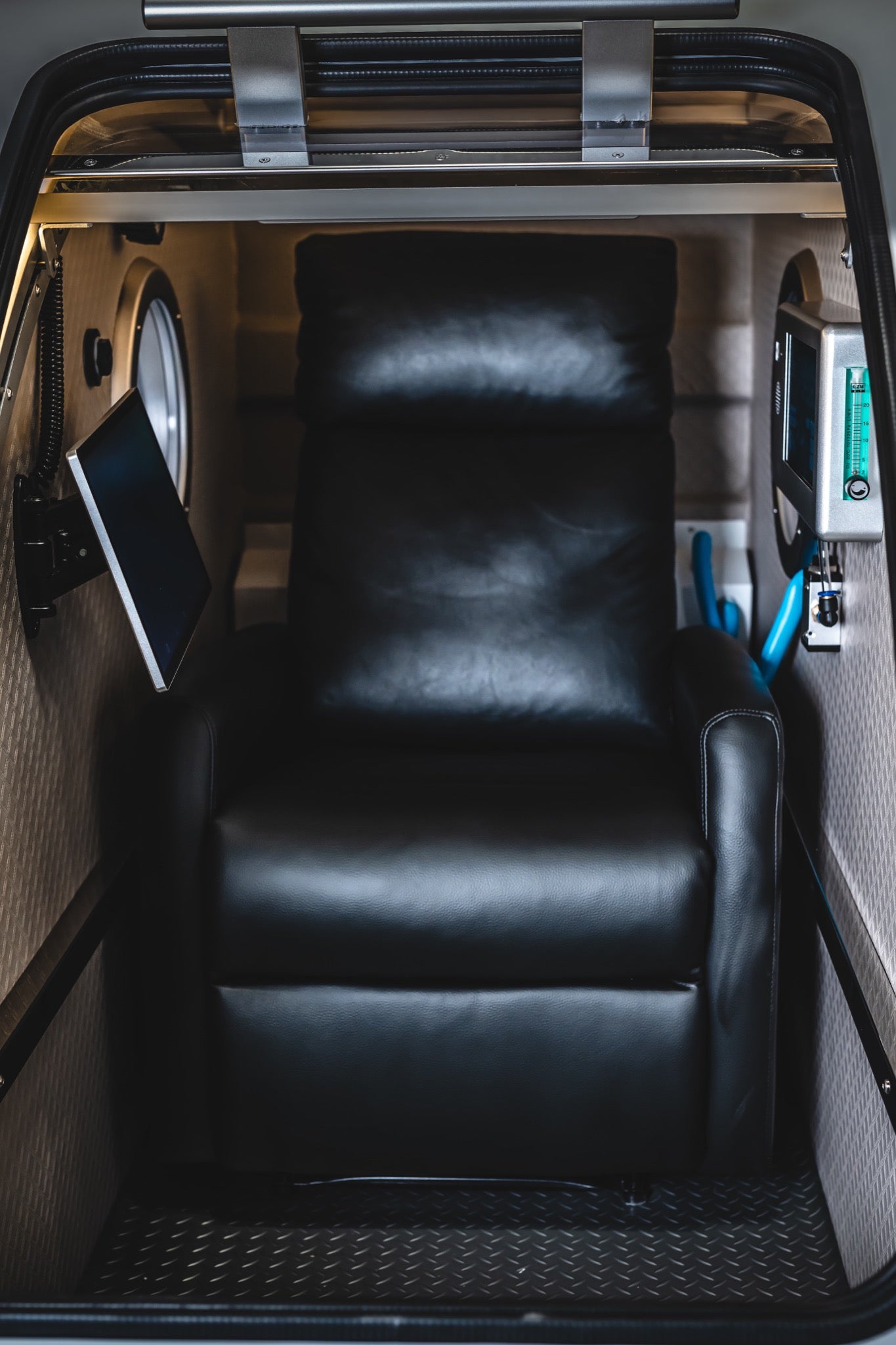 Interior of an Airvida hard-shell hyperbaric chamber featuring a reclining seat, touchscreen display, and oxygen controls.