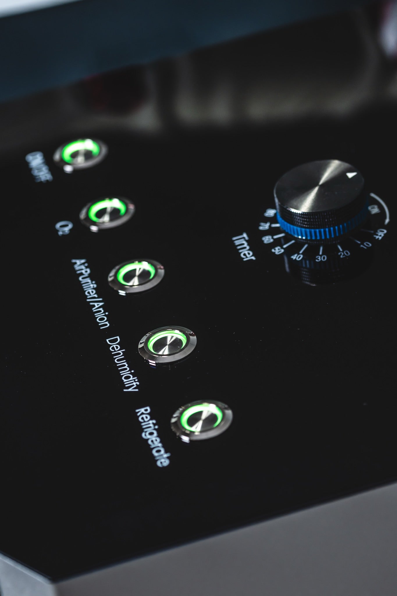 Close-up of an AIRVIDA control panel with green-lit buttons for oxygen, anion, dehumidify, refrigerate, and an adjustable timer dial.