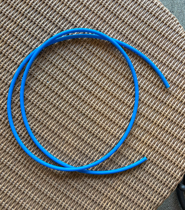 Blue flexible tubing coiled loosely on a woven wicker surface, showing a simple lightweight hose design suitable for airflow and equipment connection applications.