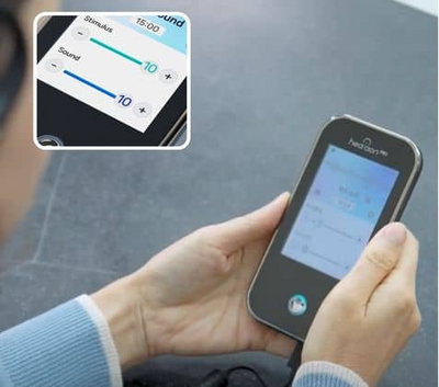 Person holding a Neurive Healaon Pro Vagus Nerve Stimulator on a gray surface