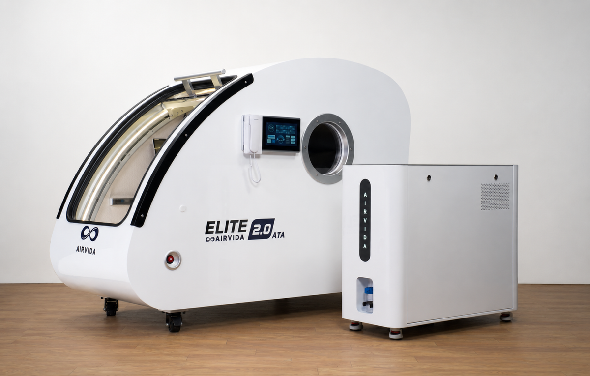 Airvida Elite 2.0 ATA hyperbaric oxygen chamber with a touchscreen, viewing port, and separate control unit displayed in a clean modern indoor setting.