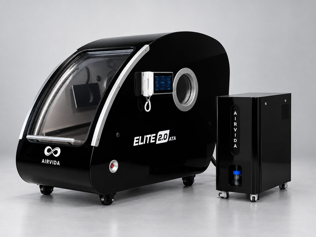 Black Airvida Elite 2.0 ATA hyperbaric chamber with curved clear door, digital controls and matching oxygen unit on wheels in a clean modern wellness setting.
