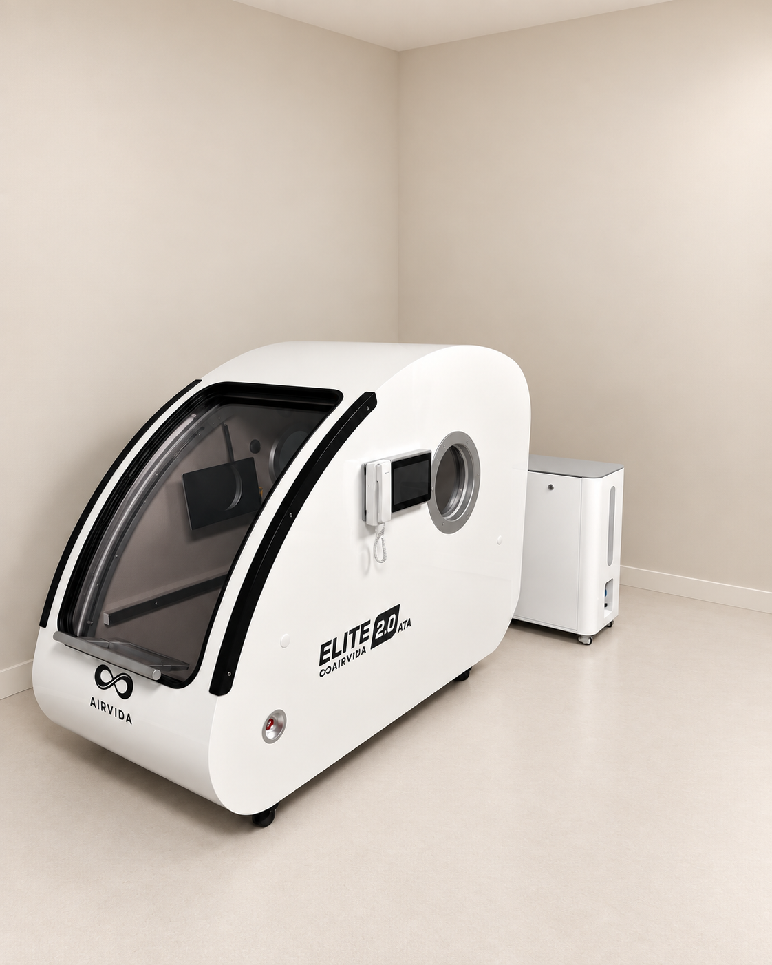White Airvida Elite 2.0 hyperbaric chamber with external oxygen system displayed in a clean minimalist room, featuring a clear door, controls, and wheels.