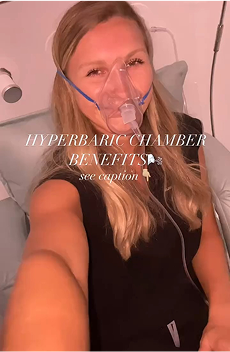 Woman wearing an oxygen mask inside a hyperbaric chamber, smiling while seated comfortably during a therapy session.