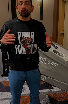 Man with beard gestures in "Pride Palestine" sweatshirt.
